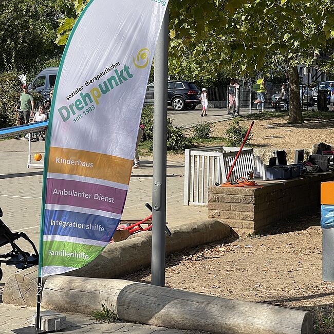 Sporterlebnistag Inklusion im Drehpunkt: Beachflag des Drehpunkts vor einem Mini Fußballfeld